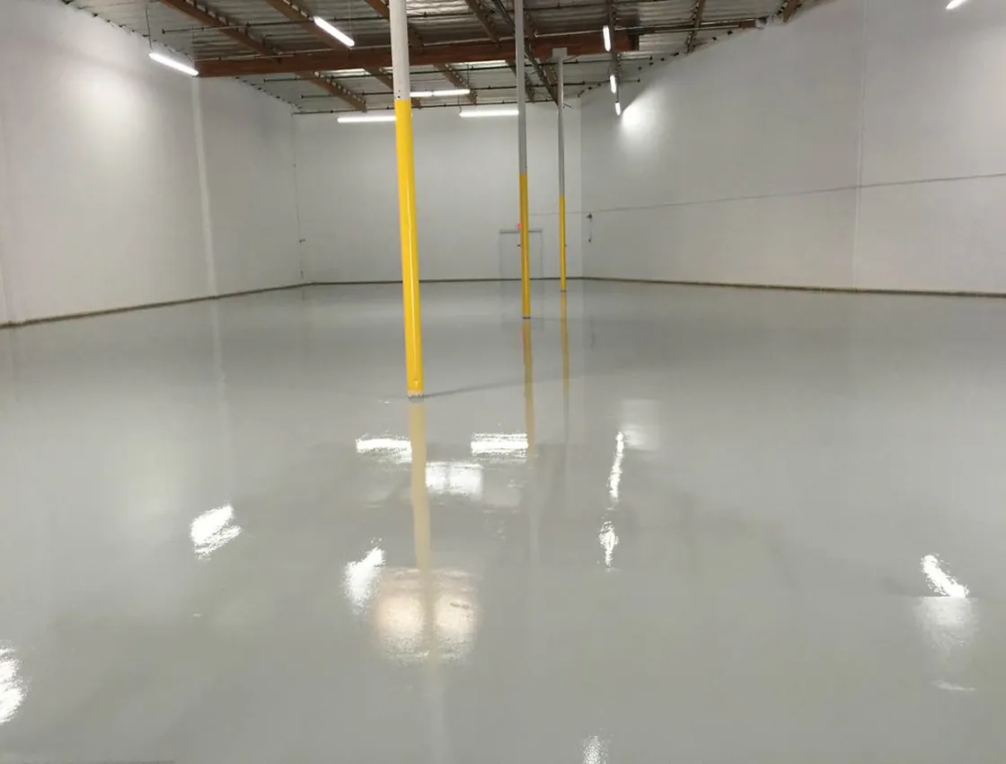 A warehouse with a sealed, glossy concrete floor reflecting overhead lights.