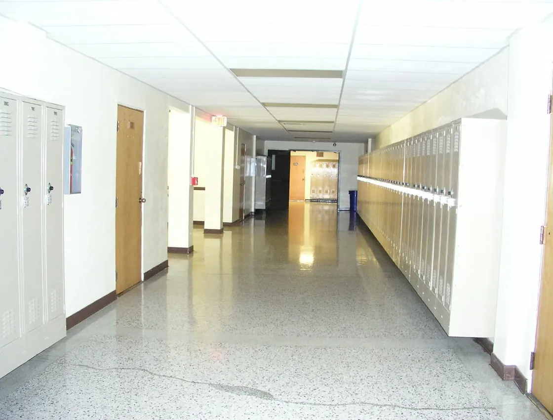A commercial corridor with a high-gloss, freshly buffed hard floor reflecting the ceiling lights.