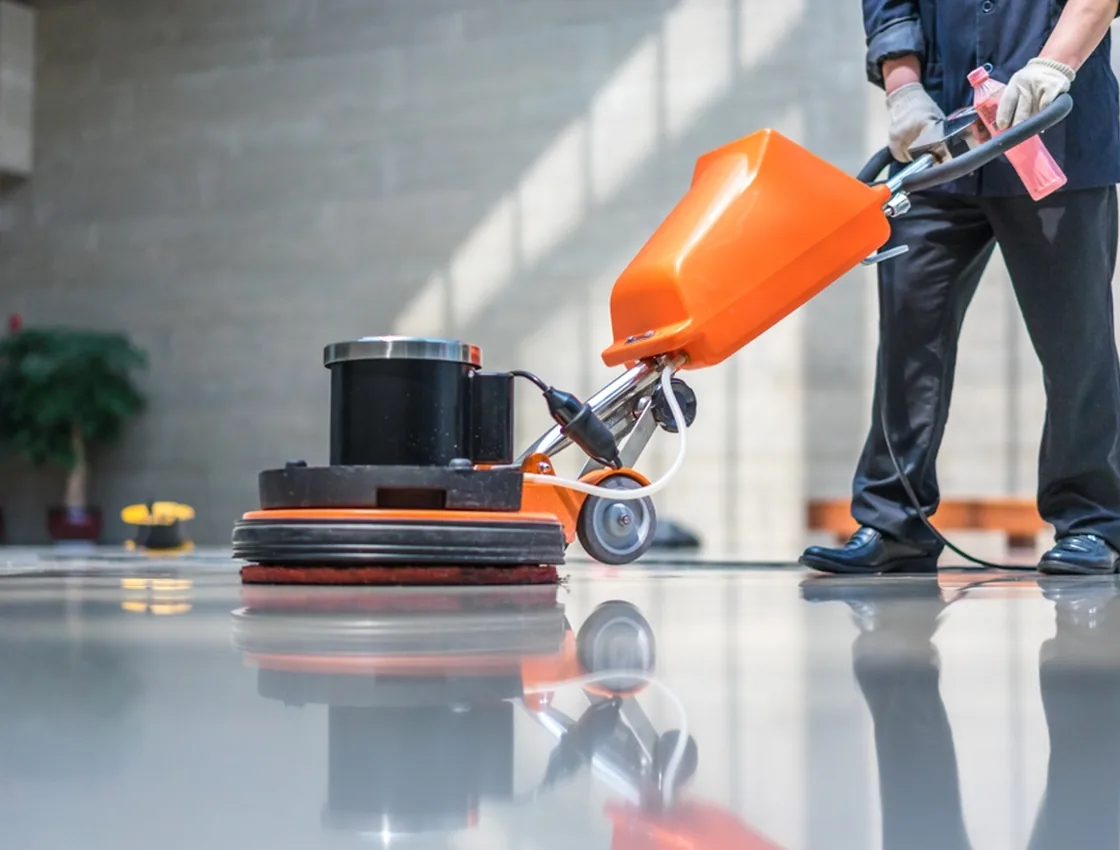 A worker operating a floor buffing machine that polishes a commercial floor to a high, wet-look gloss.